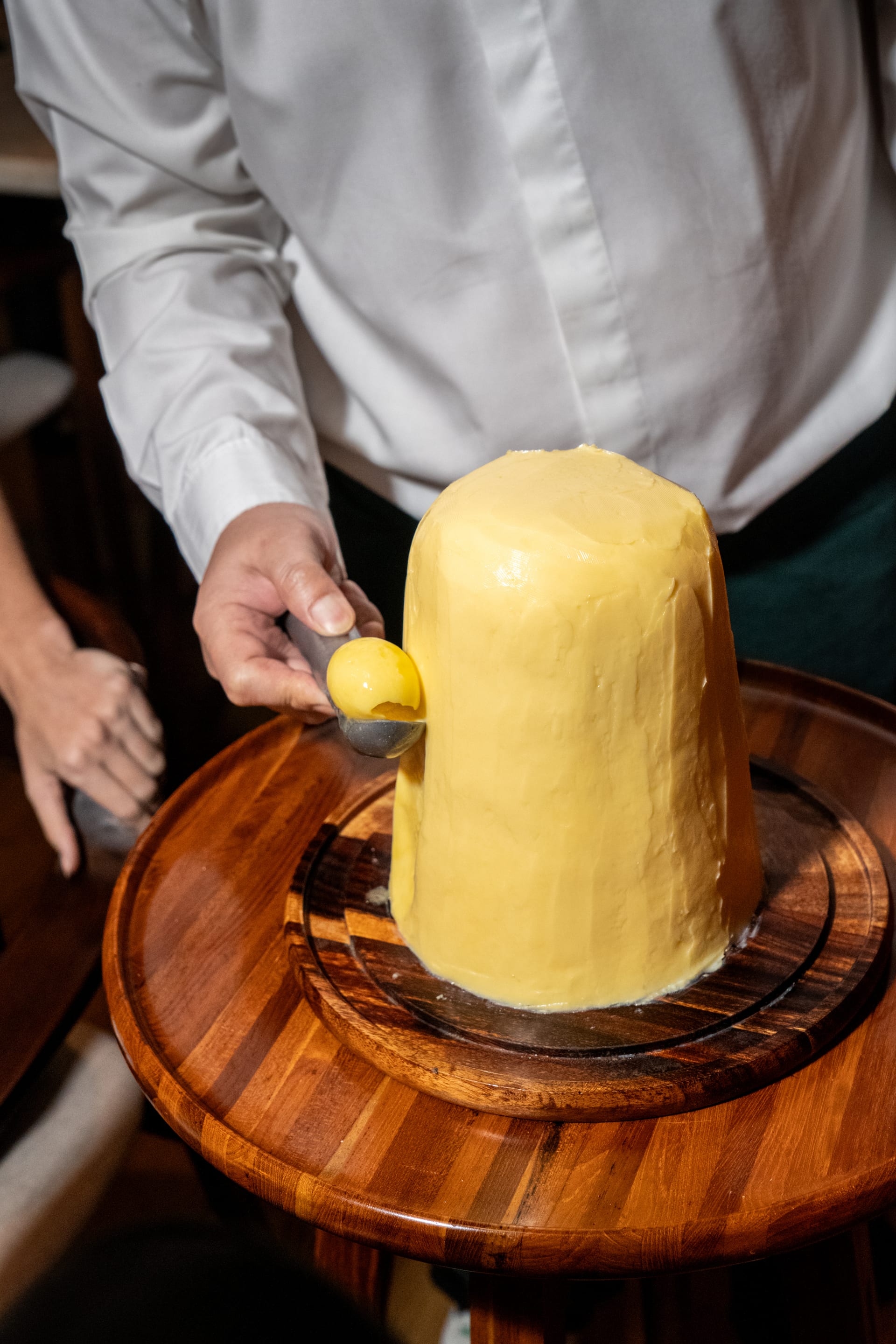 A curl of French butter being scooped from a whole block with a warm spoon at Bisou, a modern French restaurant in Cherngtalay, Phuket