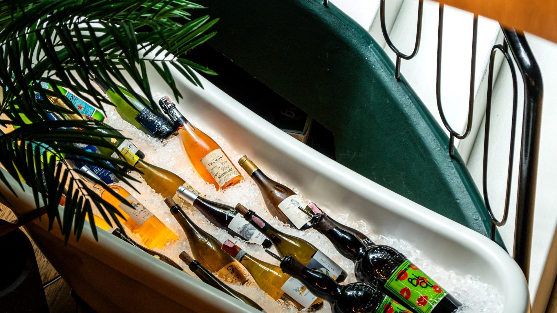 Bottles of Champagne, rosé and white wine on crushed ice in a claw-foot bathtub by the spiral staircase at Bisou Phuket, a modern French restaurant in Cherngtalay